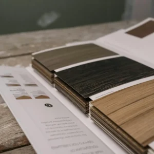 Collection of wood veneer samples displayed on a rustic wooden table indoors.